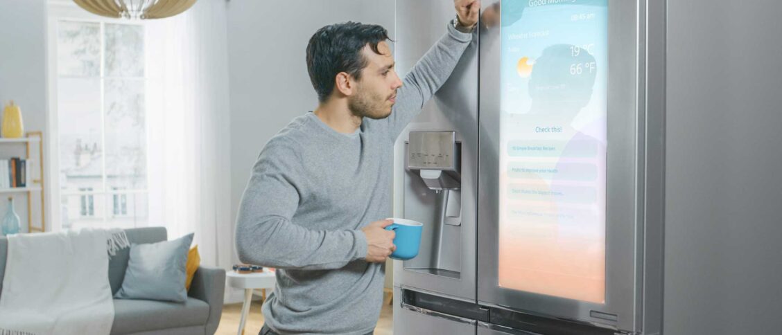 Homme qui regarde l'écran d'un réfrigérateur connecté.
