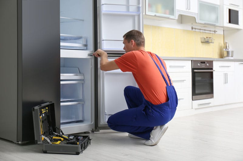 Professionnel en train de réparer un frigo