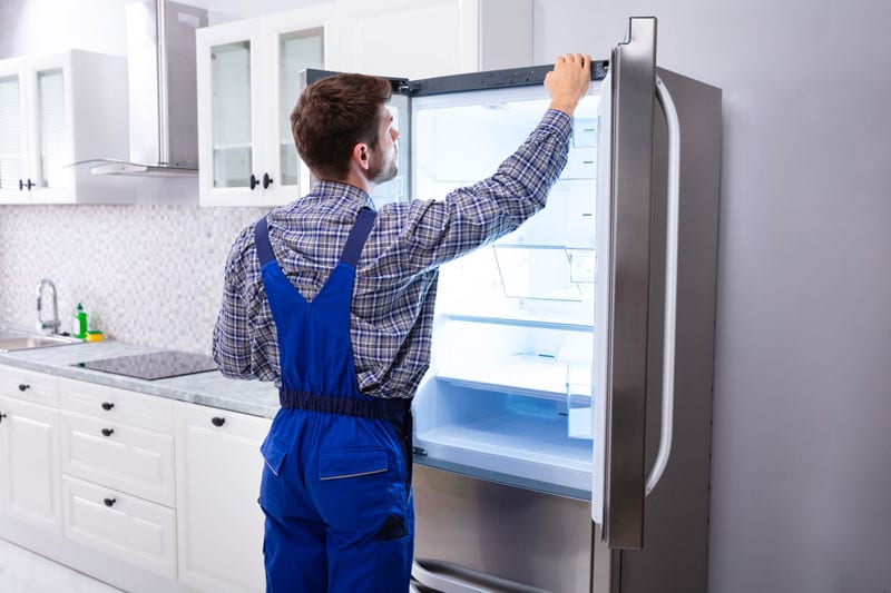 Professionnel qui analyse la panne d'un frigo