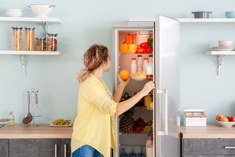 Femme qui prend un fruit dans son frigo