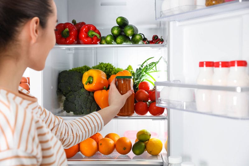 Femme qui place un aliment dans son frigo
